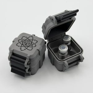 May include: Two small, grey, rectangular, rugged storage cases with black latches. One case is closed, displaying a black atom symbol graphic on its lid. The other case is open, revealing two small glass vials with silver caps inside.