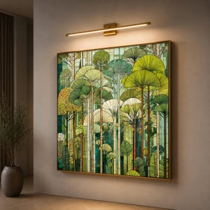 Può includere: Un'opera d'arte murale quadrata che raffigura una scena boschiva in stile vetrata con varie tonalità di verde, giallo e bianco. L'opera è incorniciata da un sottile bordo dorato ed è illuminata da una lampada orizzontale dorata sopra.