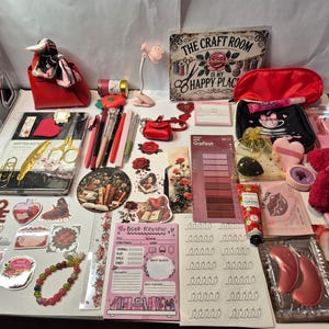 Può includere: Una collezione di articoli di cancelleria e per il fai da te che include un taccuino, penne, adesivi, un blocco per recensioni di libri, una targa in metallo con la scritta THE CRAFT ROOM IS MY HAPPY PLACE, una pochette rossa, un orsetto e maschere per labbra.