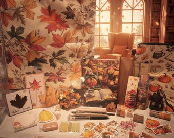 Peut inclure: Une collection de papeterie et d'accessoires sur le thème de l'automne comprenant un grand sac fourre-tout à feuilles d'érable, un carnet à spirales illustré d'une citrouille et d'un livre, des autocollants, du ruban adhésif, des stylos et une carte.