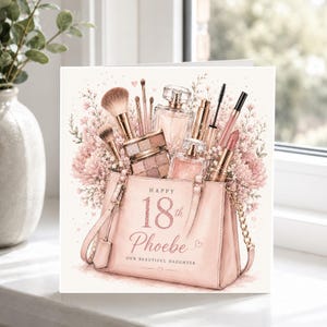 May include: A square greeting card featuring a light pink handbag filled with makeup brushes, perfume bottles, and lipstick, surrounded by pink flowers. The text reads Happy 18th Phoebe Our Beautiful Daughter in elegant script and block lettering.