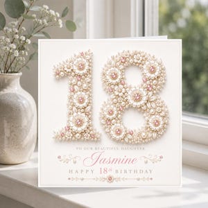May include: A square greeting card featuring the number 18 constructed from cream-colored fabric flowers, pearls, and small pink crystals. Below the number, the text reads: TO OUR BEAUTIFUL DAUGHTER Jasmine HAPPY 18th BIRTHDAY in pink and gray.