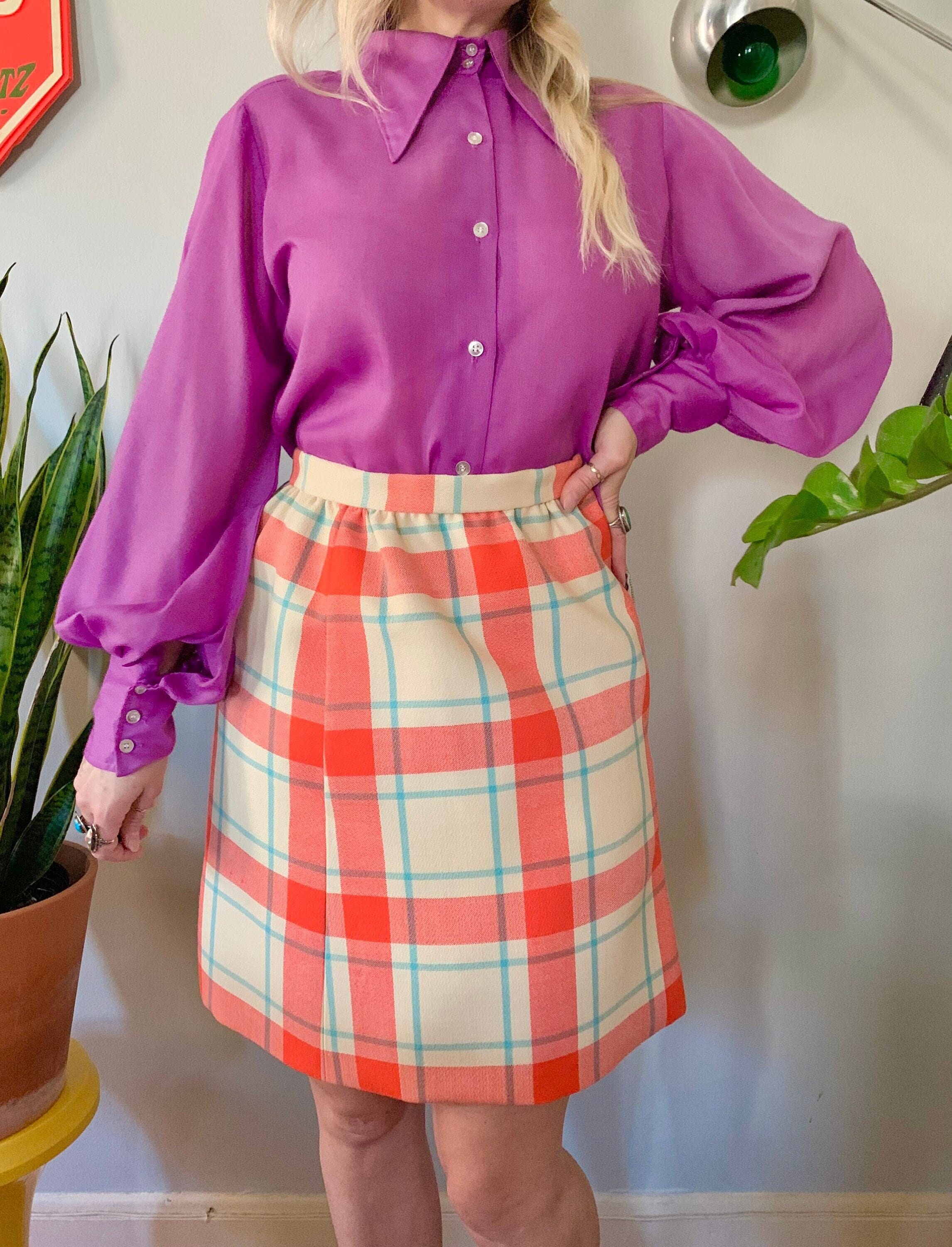 a neutral sweater, a green leather midi skirt, an orange vintage bag and  plaid flats