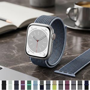 May include: A silver smartwatch with a rectangular face and a blue woven fabric strap. The watch display shows a clock face with white hands and a red second hand. A matching blue fabric strap is positioned next to the watch on the surface.