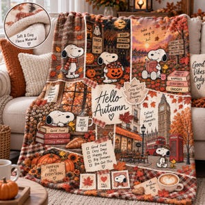 May include: A plush fleece throw blanket featuring a collage of Snoopy illustrations, autumn leaves, pumpkins, and London landmarks. The design includes text such as Hello Autumn, Pumpkin Spice Everything, and Good Food, Cozy Days, Happy Me, Big Dreams.