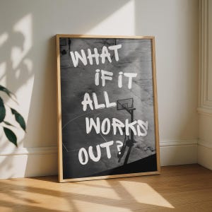 May include: A rectangular framed wall art piece featuring a black and white photograph of a basketball court. The white text overlay reads, "WHAT IF IT ALL WORKS OUT?" in a bold, hand-lettered style, centred over the court surface.