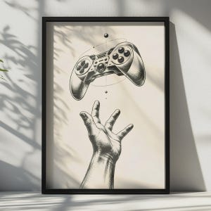 May include: A framed black and white line art print featuring a detailed illustration of a hand reaching upwards towards a floating video game controller. The controller is surrounded by thin circular lines and small dots, presented in a simple black frame.