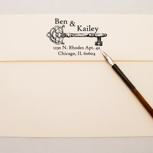 May include: A black and white illustration of a key with the text "Ben & Kailey" and the address "1230 N. Rhodes Apt. 4a Chicago, IL 60604" printed below.