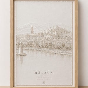 May include: A framed, textured white relief art print depicting the Málaga cityscape, including a lighthouse, cathedral, and fortress. The text reads MÁLAGA, CIUDAD DE LA LUZ, and coordinates. The bottom features the text Andalucia En La Memoria.