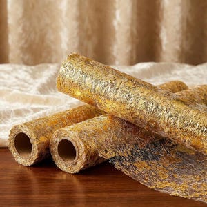 May include: Three rolls of metallic gold mesh ribbon featuring a textured, open-weave design. The material has a shimmering, foil-like finish with a grid-like structure, wound tightly around cardboard cores, displaying a reflective surface.