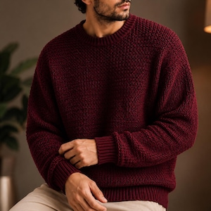 Peut inclure: Un pull à manches longues bordeaux profond doté d'un motif en tricot texturé, d'une encolure ronde classique, ainsi que de poignets et d'un ourlet côtelés. Le vêtement est confectionné avec un point dense et uniforme sur toute la surface.