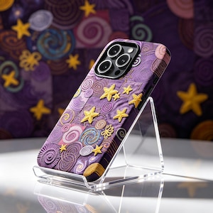 May include: A smartphone case featuring a purple background with embroidered yellow stars and circular spiral patterns. The design includes various shades of purple and pink in a quilted texture, with a prominent camera cutout at the top.