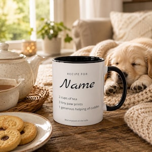 May include: A white ceramic mug with a black interior and handle, featuring the black text: RECIPE FOR Name, 2 cups of tea, 3 tiny paw prints, 1 generous helping of cuddles, and Best enjoyed on the sofa, printed on the front surface of the mug.