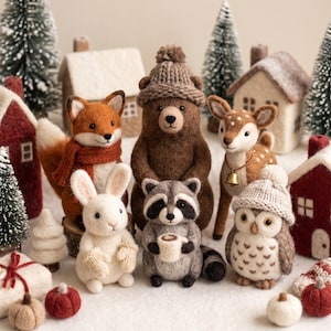 Puede incluir: Una colección de figuras de animales de lana fieltrada que incluye un zorro con bufanda, un oso con gorro de punto, un ciervo con campana, un conejo blanco con manoplas, un mapache con una taza y un búho con gorro de punto.