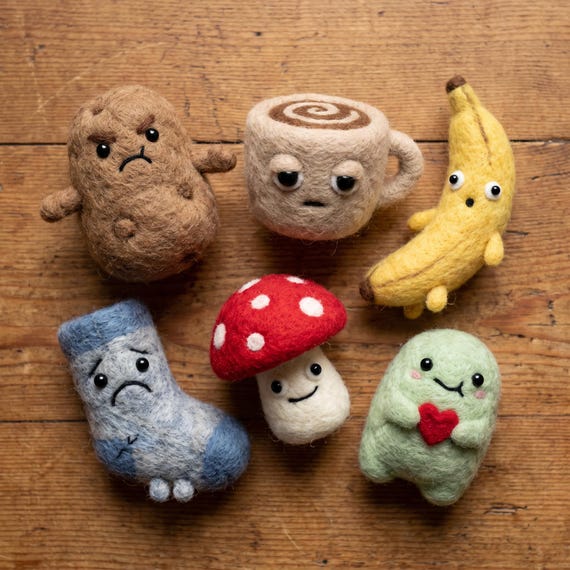 Tiny needle-felted food characters (potato, banana, mushroom) with goofy personalities — each one is a hand-sculpted wool micro-sculpture that looks like it belongs in a Studio Ghibli film.