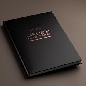 May include: A black hardcover planner with rose gold foil lettering that reads LASH TECH BUDGET PLANNER. Above the text is a small rose gold graphic of eyelashes. The planner has a smooth matte finish and is presented in a closed, angled view.