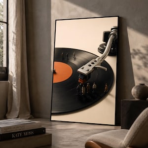 Può includere: Una stampa artistica da parete incorniciata raffigurante un disco in vinile nero con un'etichetta centrale arancione e un braccio del giradischi color argento. Minuscole figure in miniatura di persone si trovano sulla superficie del vinile.