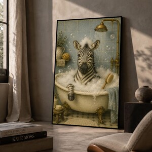 Può includere: Una stampa artistica da parete incorniciata raffigurante una zebra seduta in una vasca da bagno con piedini riempita di bolle di sapone bianche. La zebra è sotto un soffione dorato contro una parete piastrellata blu. Una spazzola è appoggiata.
