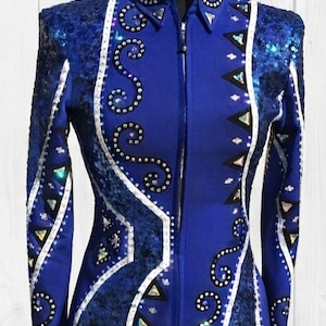 Peut inclure: Une veste de concours bleu roi avec le texte THE FRENCH CROWNS CO en haut. La veste est ornée de passepoils blancs complexes, de panneaux à sequins bleu scintillant et de motifs géométriques de cristaux clairs et irisés sur le devant.