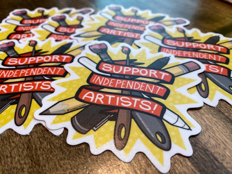Puede incluir: Una colecci&oacute;n de pegatinas con un dise&ntilde;o de estrella amarilla y el texto "SUPPORT INDEPENDENT ARTISTS!" en pancartas rojas. Las pegatinas presentan ilustraciones de materiales de arte como pinceles, l&aacute;pices y cuchillos.