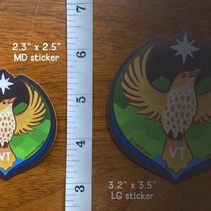 Puede incluir: Dos pegatinas con un dise&ntilde;o de p&aacute;jaro con alas extendidas, una estrella y las letras "VT". La pegatina m&aacute;s grande mide 8,1 cm x 8,9 cm, la m&aacute;s peque&ntilde;a 5,8 cm x 6,4 cm. El p&aacute;jaro tiene alas amarillas y un cuerpo moteado.
