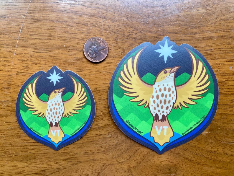 Puede incluir: Dos pegatinas con un dise&ntilde;o de p&aacute;jaro con alas extendidas, una estrella y las letras "VT". El p&aacute;jaro tiene alas amarillas y un cuerpo blanco y marr&oacute;n. Las pegatinas est&aacute;n sobre una superficie de madera, con una moneda de un centavo para la escala.