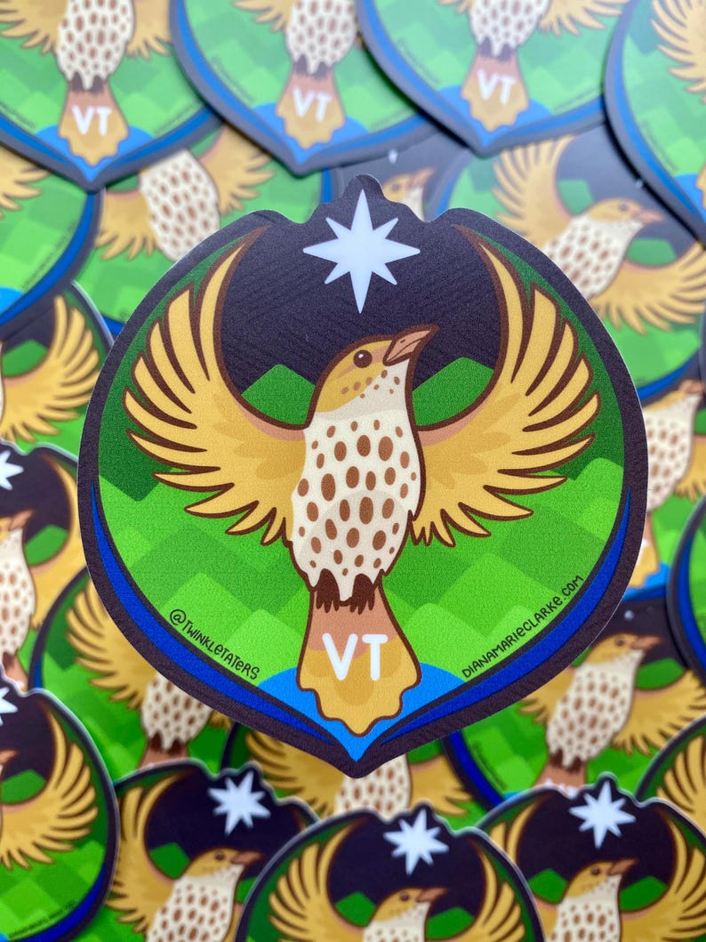 Puede incluir: Una pegatina con un p&aacute;jaro estilizado con las alas extendidas, en tonos amarillos, marrones y blancos, sobre un fondo verde y azul. La pegatina tiene un borde azul oscuro y una estrella blanca en la parte superior. Las letras "VT" est&aacute;n en la parte inferior.