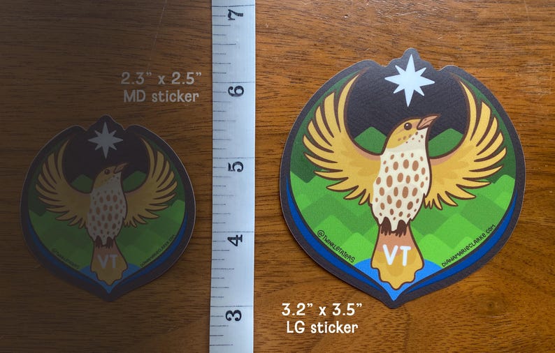 Puede incluir: Dos pegatinas con un dise&ntilde;o de p&aacute;jaro con alas extendidas, una estrella y el texto "VT". La pegatina m&aacute;s grande mide 8,1 x 8,9 cm, la m&aacute;s peque&ntilde;a 5,8 x 6,4 cm. El p&aacute;jaro tiene un cuerpo marr&oacute;n y blanco con alas amarillas.