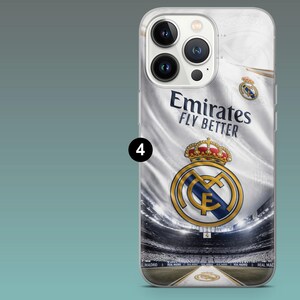 May include: A clear smartphone case featuring a graphic of a white Real Madrid jersey with the text Emirates Fly Better and the team crest. The design includes a stadium background with a crown emblem and the number 4 in a black circle.
