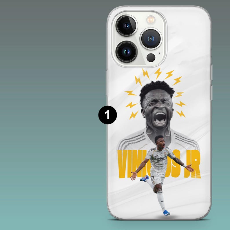 May include: A white smartphone case featuring a graphic of Vinicius Jr. in a white soccer kit. The design includes a black and white portrait of the player with yellow lightning bolts above his head and the text VINICIUS JR in yellow letters.