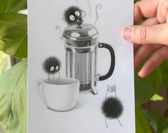 May include: A pencil drawing depicts a coffee press, a white mug, and three soot sprites. Steam rises from the press. One sprite sits atop the press, another on the mug, and a third holds a sugar cube. The artwork is held in front of a leafy green plant.
