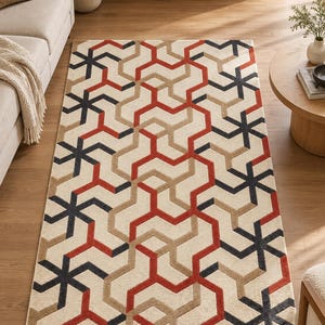 May include: A rectangular area rug featuring a repeating geometric pattern of interlocking lines in shades of dark charcoal, burnt orange, and beige against a cream-colored background, creating a structured, multi-directional visual design.