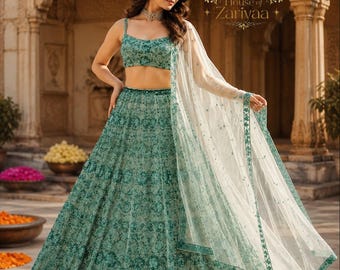 May include: A teal green lehenga set featuring a sleeveless crop top and a floor-length skirt, both adorned with intricate floral embroidery and sequins. A sheer white dupatta with a matching teal embroidered border drapes over the shoulder.