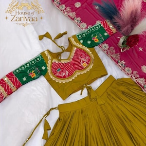 May include: A mustard yellow pleated skirt paired with a matching long-sleeved blouse featuring green sleeves, red patterned panels, and gold trim. A separate magenta fabric piece with intricate silver embroidery and a floral border is included.
