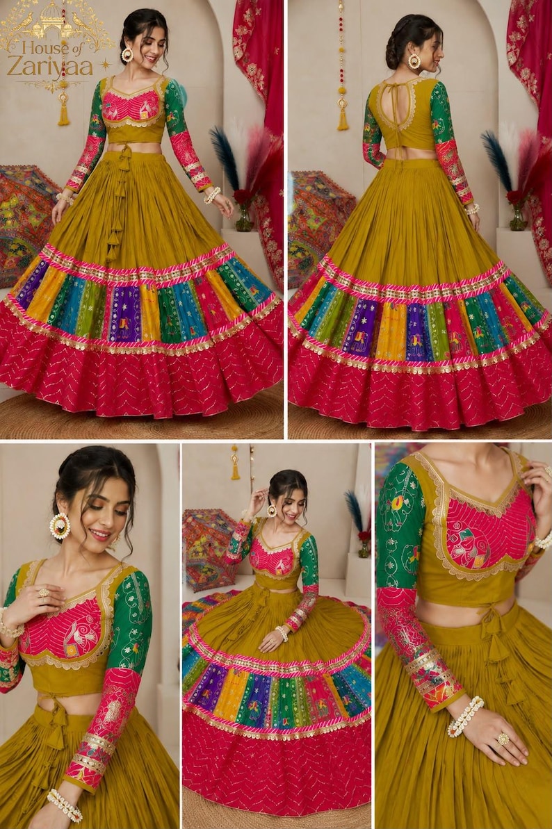May include: A mustard yellow lehenga choli set featuring a cropped blouse with green and pink patterned sleeves, and a long, pleated skirt with a wide, multi-colored panel border in blue, yellow, and green, finished with a solid pink hem.