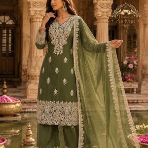 May include: An olive green salwar kameez set featuring a long-sleeved tunic and wide-leg trousers. The garment is adorned with intricate cream-colored embroidery on the neckline, sleeves, and hem, paired with a matching sheer olive green dupatta.