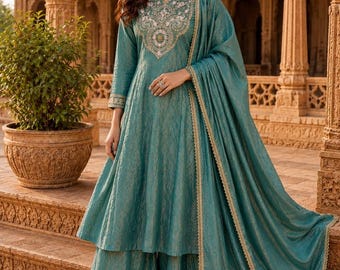 Può includere: Un completo a tre pezzi color blu ottanio composto da una tunica a trapezio a maniche lunghe con intricati ricami bianchi e dorati intorno allo scollo, pantaloni a gamba larga e una dupatta abbinata con bordo dorato, etichettato House of Zariyaa.