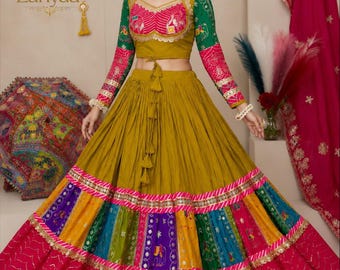 Peut inclure: Un ensemble lehenga choli jaune moutarde composé d'un haut court à manches longues vertes et roses à motifs. La jupe présente une large section supérieure plissée jaune moutarde, un panneau multicolore brodé et un ourlet rose foncé.