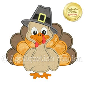 May include: A Thanksgiving-themed applique design featuring a cartoon turkey wearing a pilgrim hat. The turkey has a beige body, orange beak, and a red wattle. The design includes the text "Appliquation Station Exclusive".