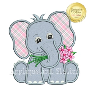 Op de afbeelding: Een grijze olifant met roze en grijs geruite oren die een boeket roze bloemen vasthoudt. De olifant zit en glimlacht. De tekst "Appliquettion Station" staat onder de olifant.