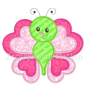 Puede incluir: Una mariposa verde con un cuerpo en forma de coraz&oacute;n rosa y lunares blancos. La mariposa tiene una cara linda con ojos negros y una nariz rosa.