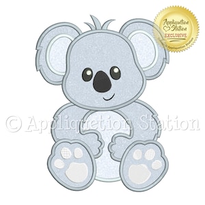 May include: A light blue embroidered koala bear applique design with white accents. The koala is sitting with its arms crossed and has a cute, smiling face.