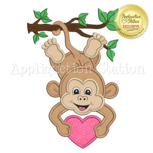 May include: A brown monkey with a pink heart hanging upside down from a tree branch. The monkey is holding the heart in its hands. The text "Appliquetion Station Exclusive" is on a gold star sticker in the upper right corner of the image.