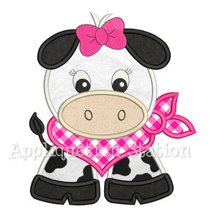 Może przedstawiać: Biała krowa z czarnymi plamami i różową kokardką na głowie. Krowa nosi różową i białą kratkowaną chustkę wokół szyi. Krowa stoi na czterech nogach i ma przyjazny wyraz twarzy.