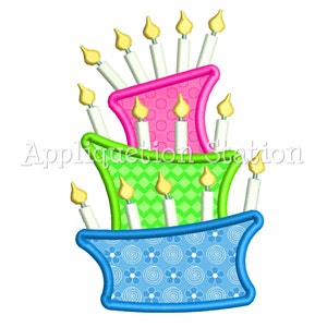 Może przedstawiać: Trzywarstwowy tort urodzinowy z różowym, zielonym i niebieskim lukrem. Tort jest ozdobiony białymi świeczkami i wzorem białych kropek na górnym piętrze.