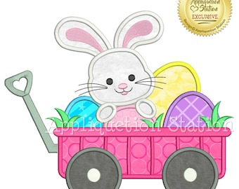 May include: A white bunny with pink ears sits in a pink wagon with a heart-shaped handle. The wagon is filled with colorful Easter eggs. The bunny is holding a pink egg.