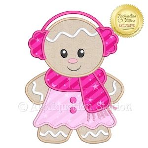 Puede incluir: Un diseño de galleta de jengibre con una cara sonriente, que lleva orejeras rosas, una bufanda rosa con estrellas y un vestido rosa. El diseño incluye el texto "Appliquation Station Exclusive".