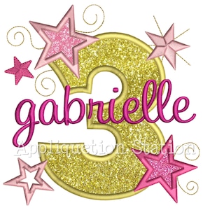 May include: Gold glitter number three with pink stars and the name gabrielle in pink cursive lettering.