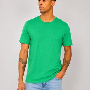 Op de afbeelding: Een effen felgroen T-shirt met korte mouwen en een ronde halslijn. Het kledingstuk heeft een eenvoudig, strak ontwerp met een rechte zoom en een standaard pasvorm, gemaakt van een gladde stof die gelijkmatig over de romp valt.