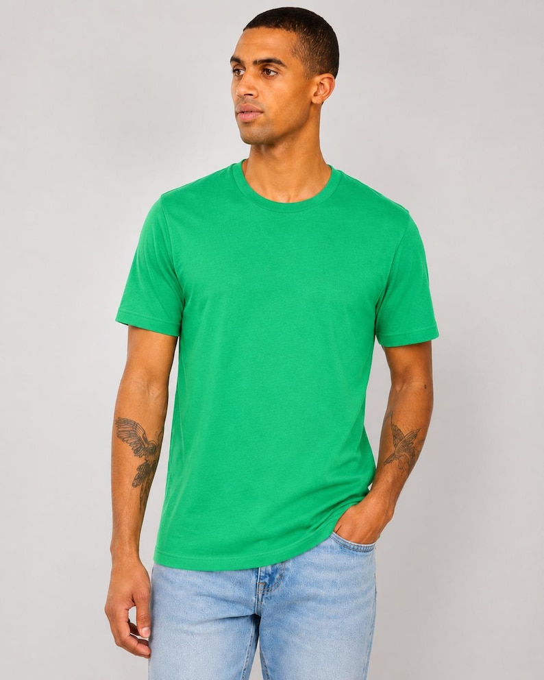 Op de afbeelding: Een effen felgroen T-shirt met korte mouwen en een ronde halslijn. Het kledingstuk heeft een eenvoudig, strak ontwerp met een rechte zoom en een standaard pasvorm, gemaakt van een gladde stof die gelijkmatig over de romp valt.